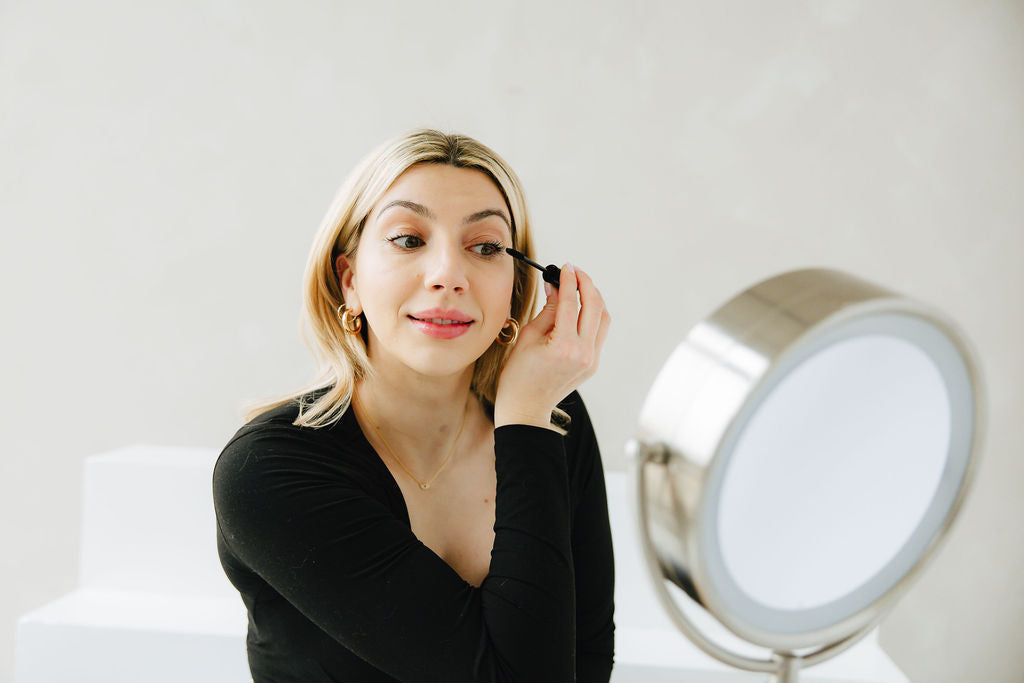 Woman applying Jennifer Lane Beauty's Lane Lashes Mascara in front of a magnifying mirror