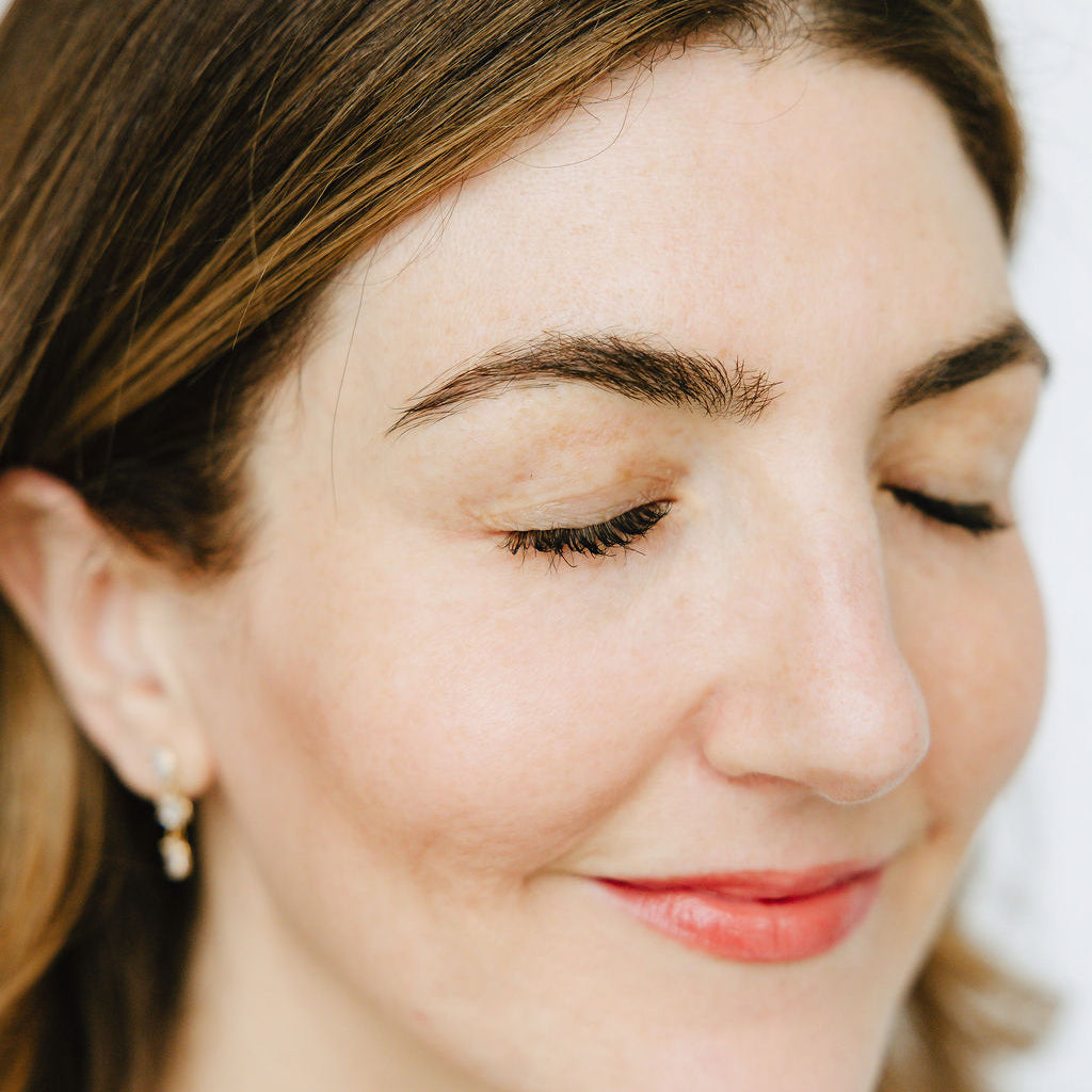 Woman's thick, full, and dark lashes after applying Jennifer Lane Beauty's Lane Lashes mascara with a white background