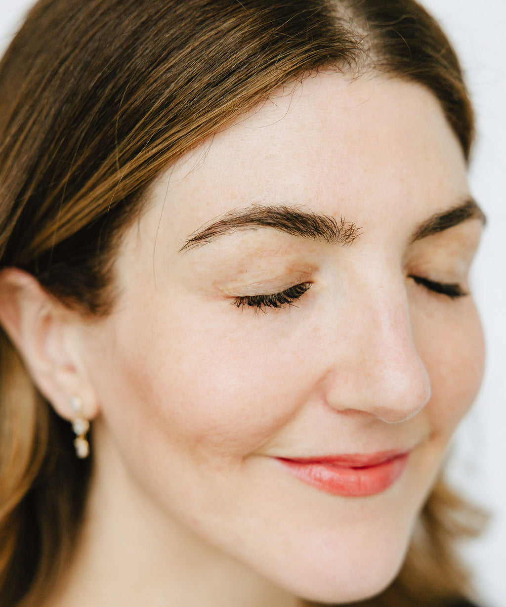 Woman's thick, full, and dark lashes after applying Jennifer Lane Beauty's Lane Lashes mascara with a white background