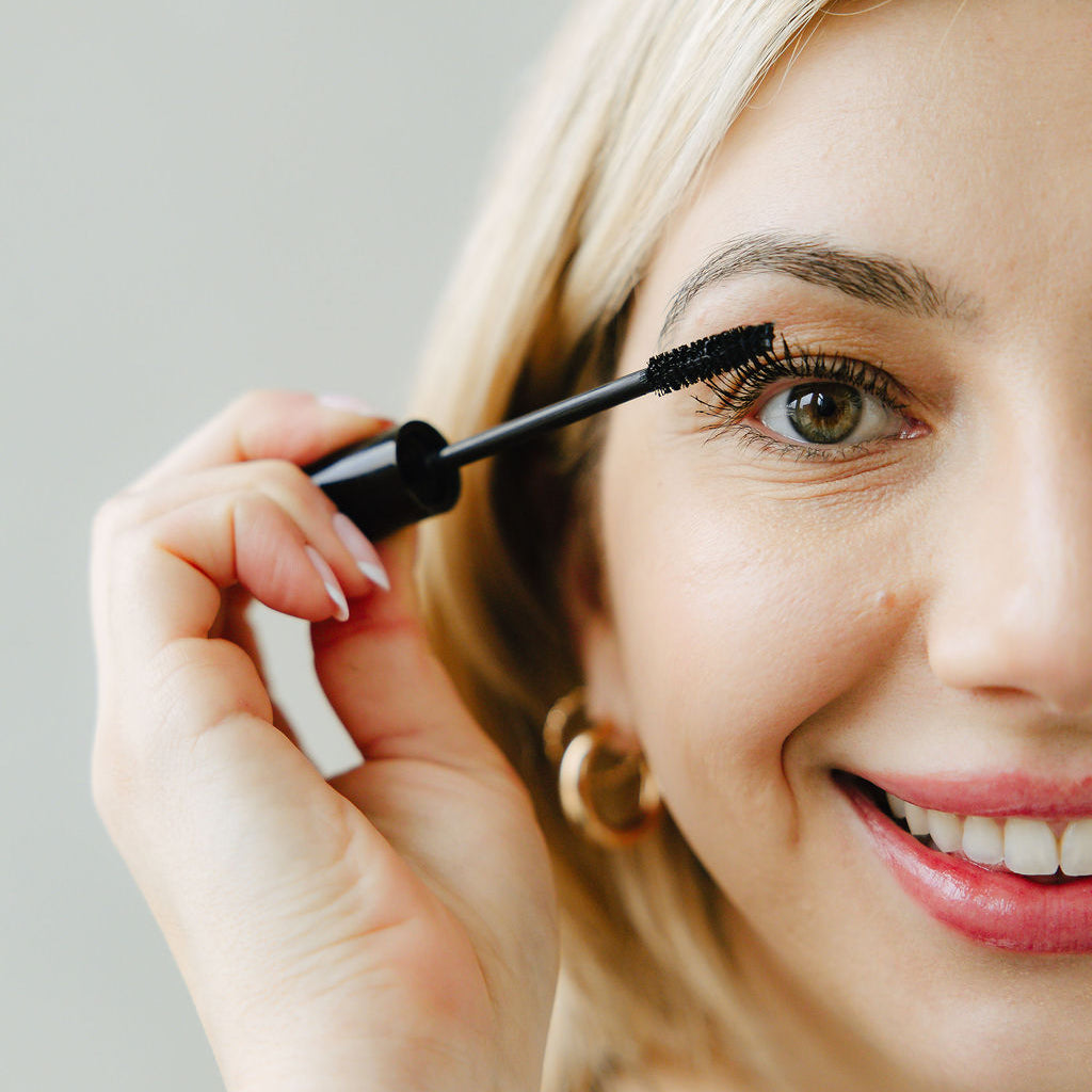 Woman applying Jennifer Lane Beauty's Lane Lashes mascara with a white background