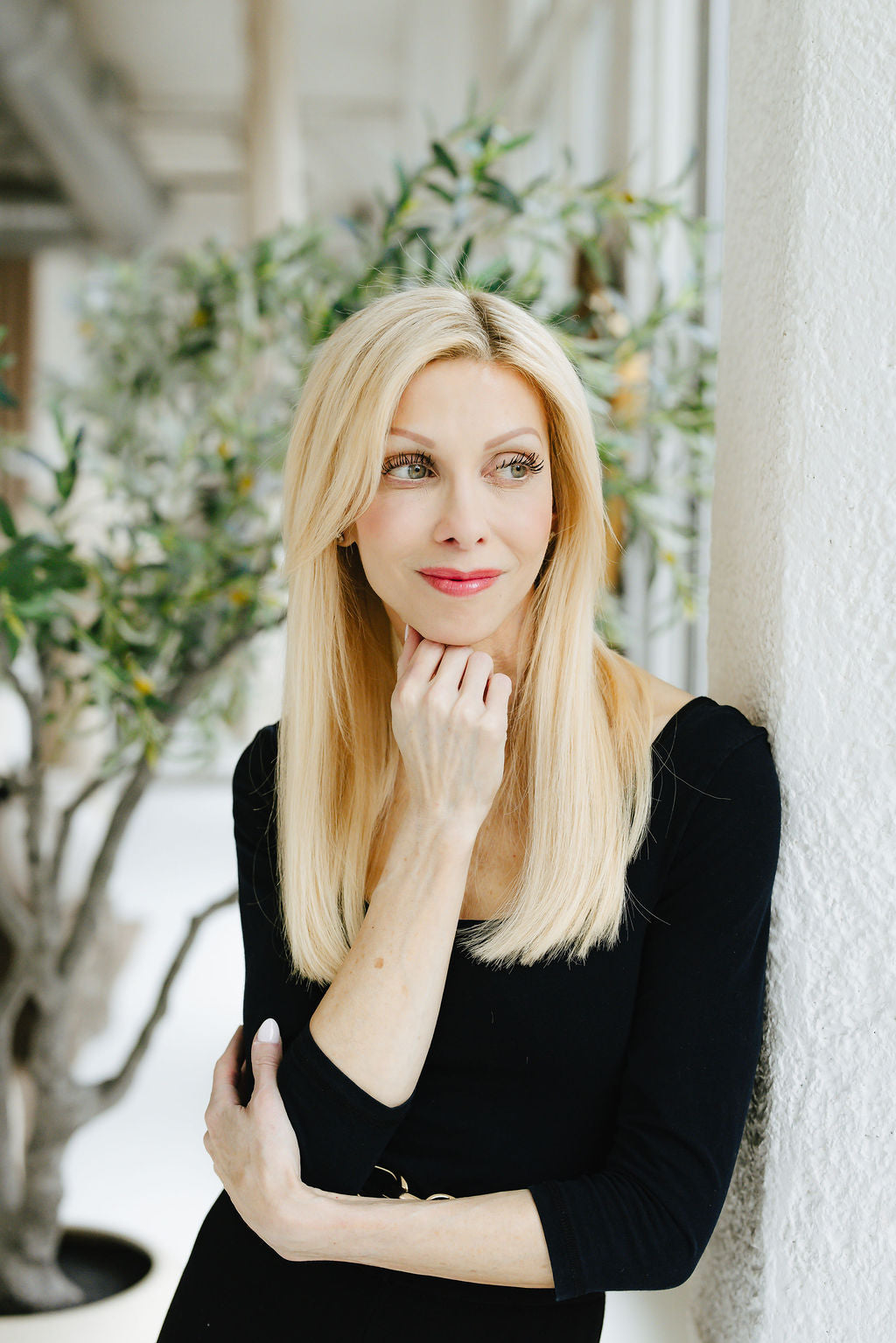 Founder, Jennifer Lane, leaning against a white pillar and looking out the window