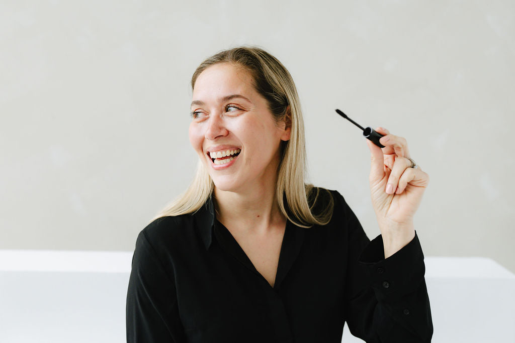 Woman applying Jennifer Lane Beauty's Lane Lashes mascara with a white background