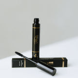Black, highly pigmented Lane Lashes Mascara with applicator and packaging on a white surface